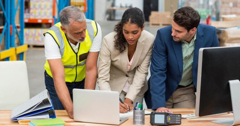 Warehouse managers and worker discussing with laptop