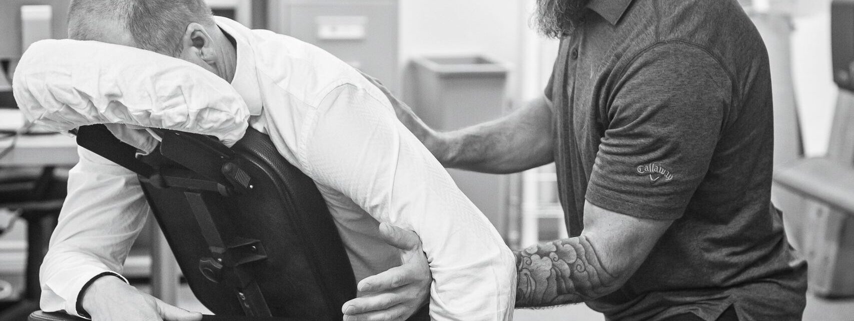 Massage therapist assisting client in a clinical setting. Promotes wellness and workplace health.